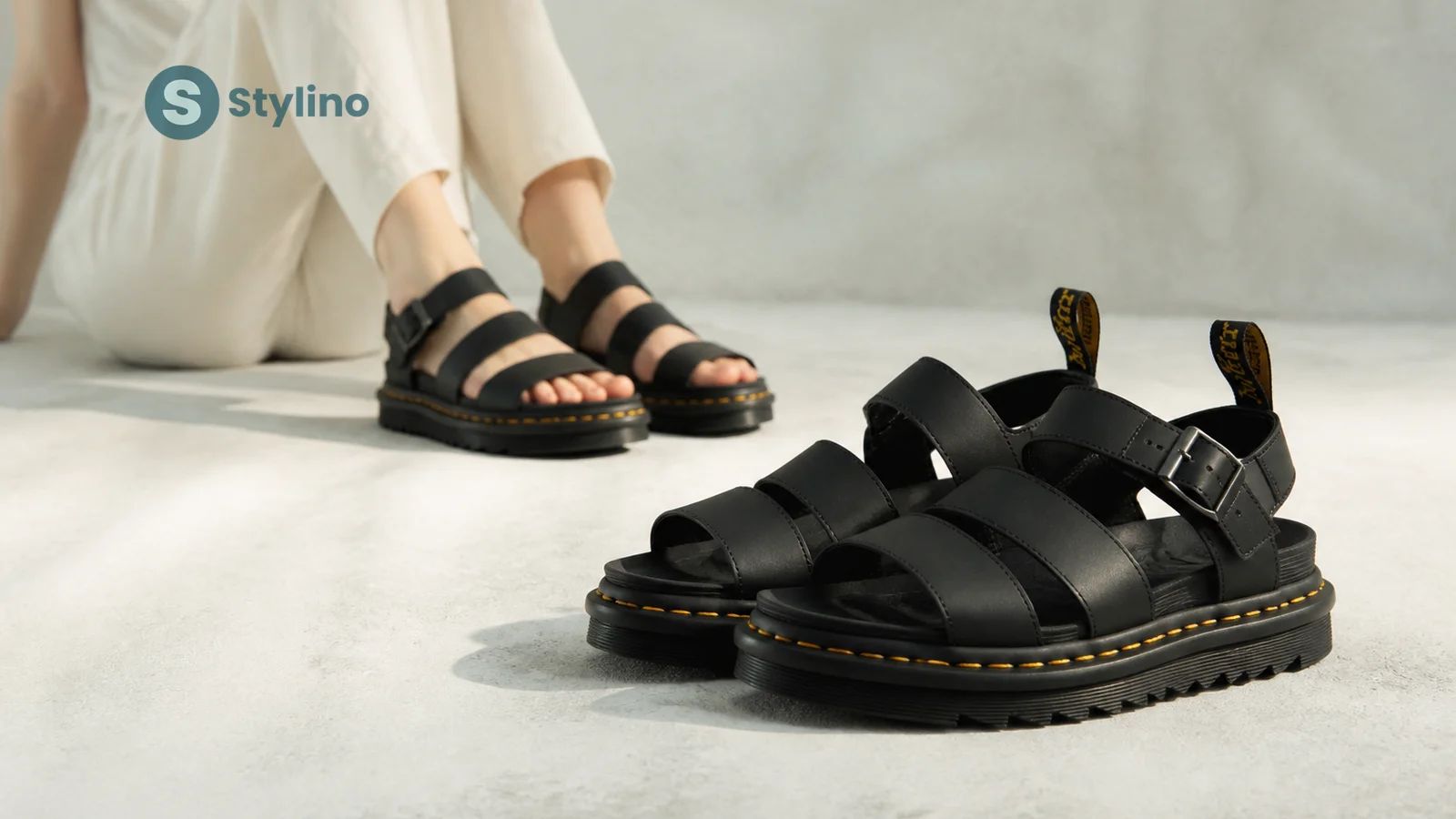 Dr. Martens Blaire σανδάλι σε μαύρο δέρμα με κίτρινη ραφή και σόλα AirWair σε εκδοτικό teal φόντο